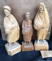 Three Caron wood carved women figures on black cloth