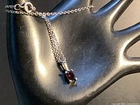 Necklace draped on display hand showing pendant, chain, clasp