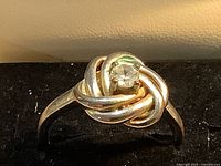 Front view of gold-tone knot ring displaying central round clear stone