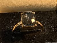 Ring front view showing emerald-cut clear stone and prong setting