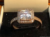 Square-cut clear stone halo ring shown in case