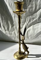 Front view of brass candle holder showing rabbit figure and cup