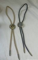 Both bolo ties full length with cords and tips visible