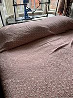 Full view of bed showing pink woven bedspread