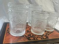 Group of embossed glass tumblers on top of placemat showing pattern and texture