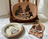 All three plaques grouped: oval terracotta, round stoneware, scroll-form terracotta