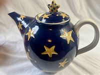 Side view of cobalt teapot with yellow stars and star finial lid