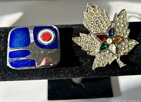 Both brooches side by side on display stand