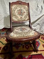 Front view of folding rocking chair with needlepoint upholstery
