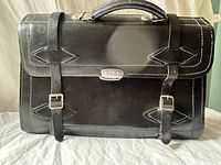 Front view showing latch, buckle straps, handle, stitching