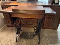 Closed Singer treadle cabinet showing cast-iron base and wood drawers