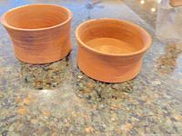 Pair of round turned wooden bowls on counter, showing interior and exterior