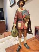 Front view of painted resin pilgrim statue holding turkey and satchel