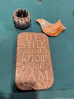 Front view of three items: plaque, lotus tealight holder, ceramic bird