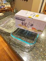 Overall lot on countertop: boxed rotary grater, pressed glass tray, Pyrex dish