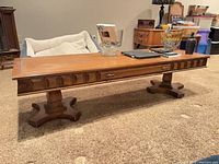 Rectangular solid wood coffee table with carved front and pedestal base