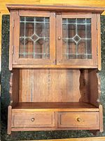 Front view of wood wall cabinet with leaded glass doors closed and drawers in place