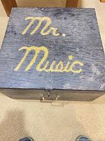 Top view of closed wooden box showing hand-painted “Mr. Music”
