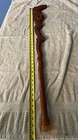 Full length view of carved fish cane with measuring tape showing approx 34 inches