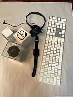 All items laid out: Apple keyboard, Apple Watch, headphones, two color sensors with packaging