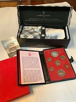 Overall view showing Valerio Garati gift box opened with ties, pocket square, cufflinks; coin set case; small boxed item