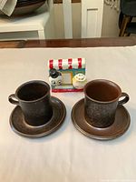 Front view of two Ruska cups with saucers and novelty napkin holder with shakers