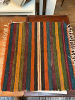 Full view of multicolour striped saddle blanket showing overall design and fringed edges