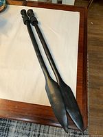 Full view of both ebony spears on table surface