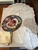 Group view of crochet doilies, needlepoint panel, embroidered linen pieces and napkins