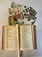 Open book, recorder, banknotes, coins overview