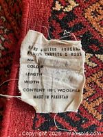 Fabric tag showing hand knotted Bokhara 100% wool pile, made in Pakistan