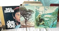 Front view showing Paul Simon, unidentified tree-cover album, and Joni Mitchell For The Roses in front of stack