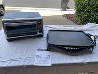 Hamilton Beach griddle, Black & Decker toaster oven and instruction sheet on table