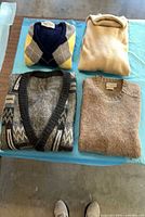 Four folded sweaters showing colours and patterns