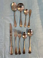 Group of assorted flatware pieces laid out including serving utensils, knife, forks and spoons