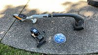Full view of Ryobi 18V string trimmer, charger, battery and line spool on ground