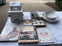 Full lot showing pasta maker, discs, bowls, cookbooks