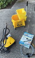 Wagner steamer, hose, accessories and Rubbermaid bucket on driveway