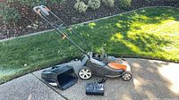 Full mower with grass bag and charger on driveway