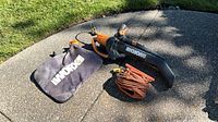 Worx WG505 blower/vac/mulcher with bag and extension cord displayed on pavement