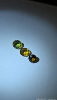 Three faceted tourmaline gemstones on white surface