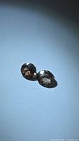 Pair of oval faceted zircons on blue background