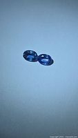 Pair of oval blue sapphires on neutral background