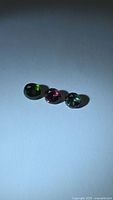 Three loose faceted round tourmaline gemstones on white background