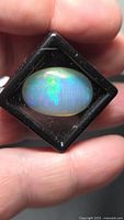 Front view of oval Ethiopian opal in holder showing play of color