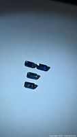 Four rectangular deep blue sapphires on white background under light