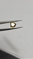 Heart-cut yellow Chrysoberyl held in tweezers