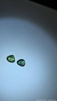 Pair of triangular green-blue sapphires on light background