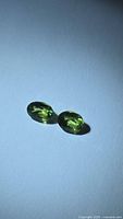 Pair of oval green sapphires on white background