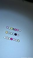 Three rows of small multicolor round sapphires on white surface